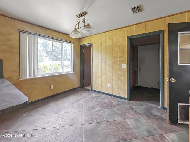 empty room with wooden walls, visible vents, and baseboards