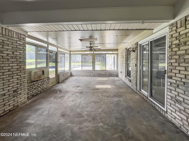 unfurnished sunroom with ceiling fan, beamed ceiling, and a wall mounted air conditioner