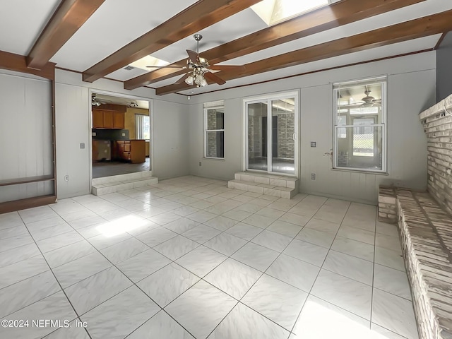 unfurnished living room with light tile patterned floors, a ceiling fan, a skylight, and beam ceiling