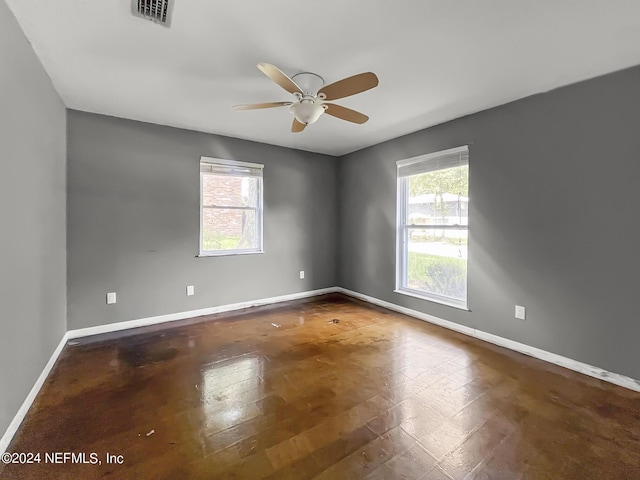 empty room featuring visible vents, a wealth of natural light, and baseboards