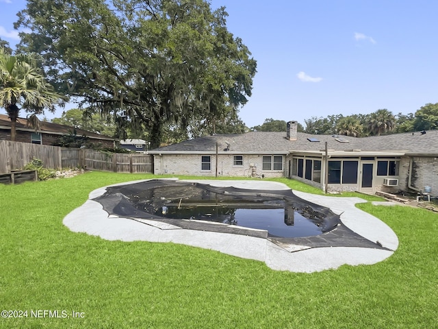 back of property featuring a sunroom, a fenced backyard, a chimney, a yard, and brick siding