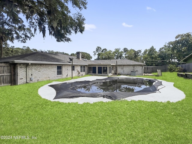 rear view of property featuring a fenced in pool, a fenced backyard, a lawn, and brick siding