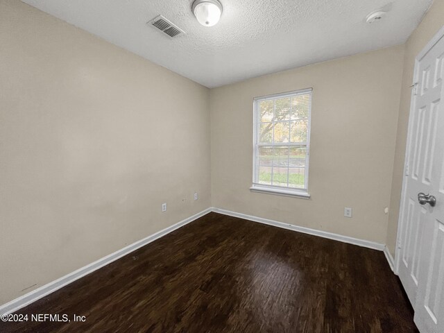 unfurnished room with hardwood / wood-style flooring and a textured ceiling