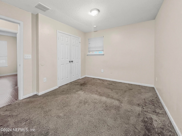 unfurnished bedroom with carpet, a closet, and a textured ceiling