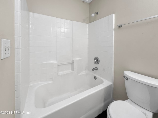 bathroom featuring tiled shower / bath combo and toilet