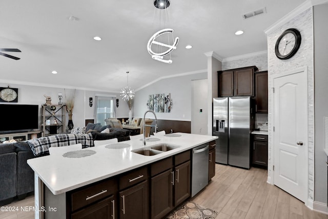 kitchen featuring sink, decorative light fixtures, a center island with sink, ornamental molding, and appliances with stainless steel finishes