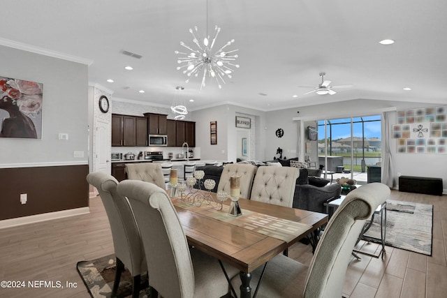 dining area with lofted ceiling, sink, ornamental molding, and light hardwood / wood-style floors