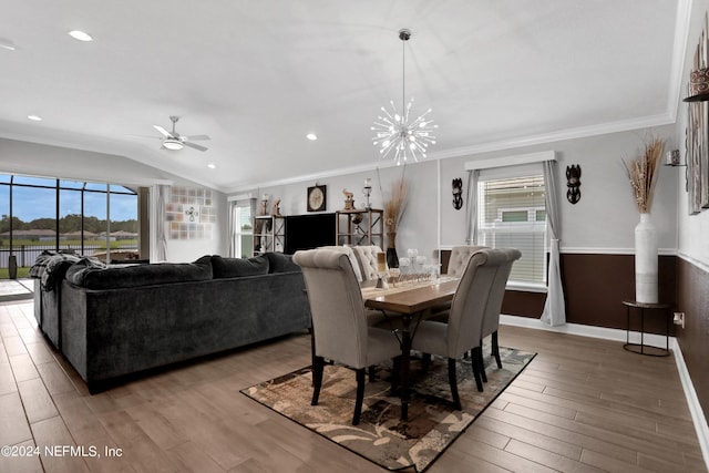 dining room featuring vaulted ceiling, ornamental molding, ceiling fan with notable chandelier, and hardwood / wood-style floors