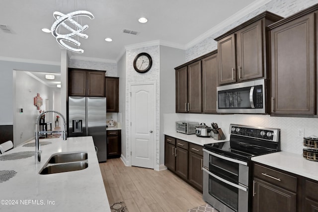 kitchen with pendant lighting, sink, dark brown cabinetry, and appliances with stainless steel finishes