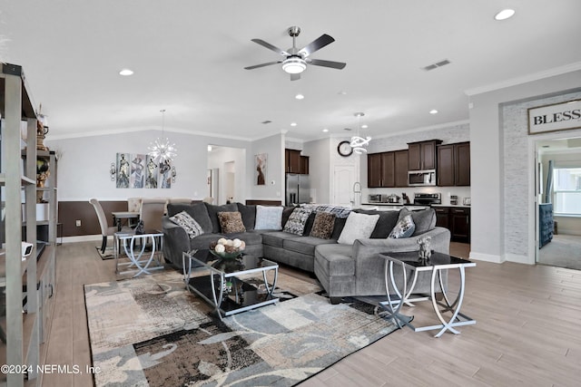 living room with ceiling fan with notable chandelier, ornamental molding, sink, and light hardwood / wood-style floors