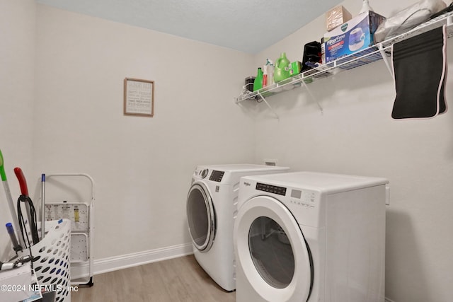 washroom with washing machine and clothes dryer and light wood-type flooring