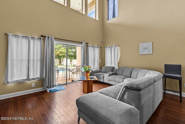 living room featuring a towering ceiling and dark hardwood / wood-style floors