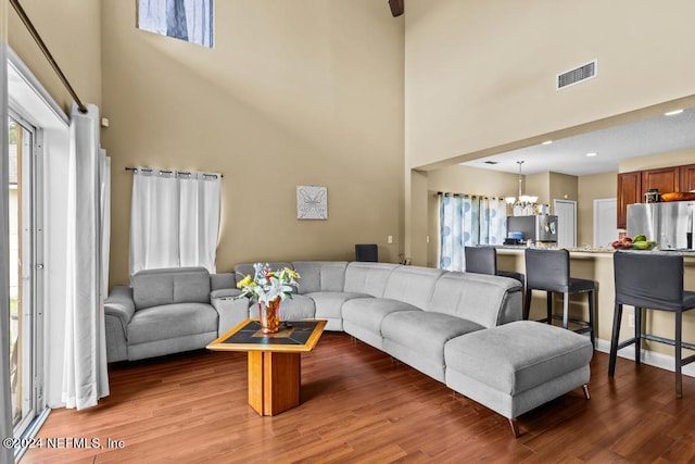 living room with wood-type flooring, a chandelier, and a towering ceiling