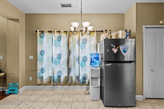 interior space featuring a textured ceiling, an inviting chandelier, stainless steel fridge, and tile patterned floors