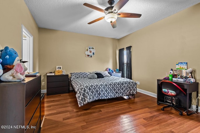 bedroom featuring ceiling fan, dark hardwood / wood-style flooring, and a textured ceiling