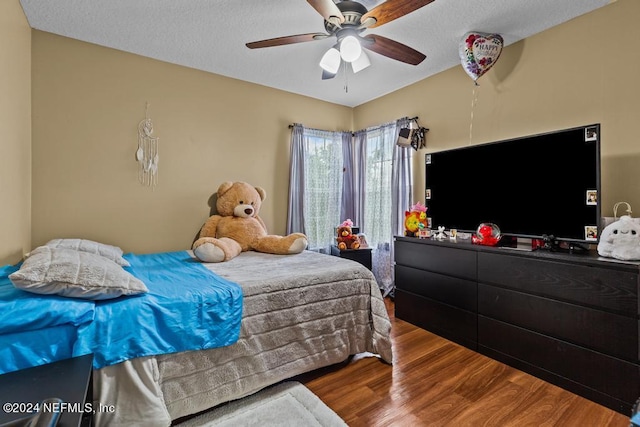 bedroom featuring hardwood / wood-style floors, ceiling fan, and a textured ceiling