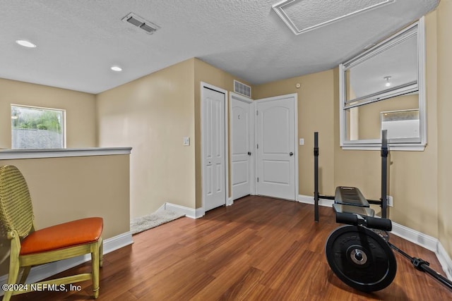 exercise room with dark hardwood / wood-style floors and a textured ceiling