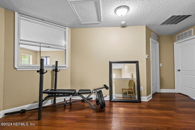 workout area with a textured ceiling and dark wood-type flooring