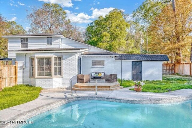 back of property with an outdoor structure, a fenced in pool, and a patio area