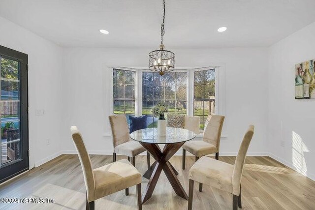 dining area with light hardwood / wood-style flooring and an inviting chandelier