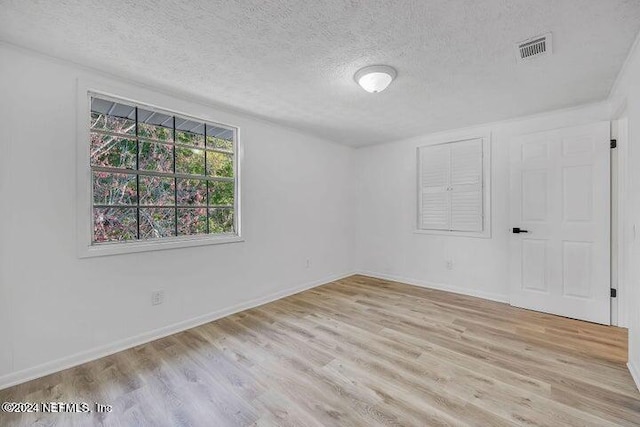 empty room with a textured ceiling and light hardwood / wood-style floors