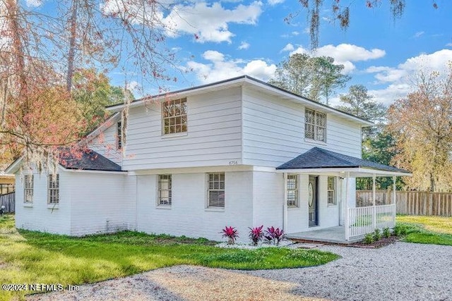 back of property featuring a lawn and covered porch