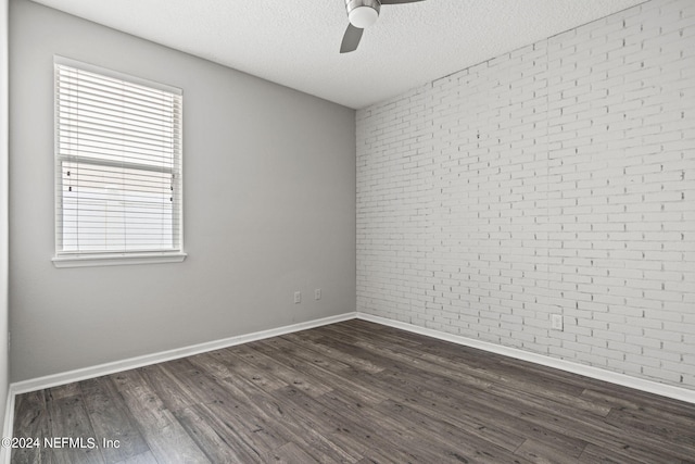 unfurnished room featuring ceiling fan, dark hardwood / wood-style floors, brick wall, and a textured ceiling