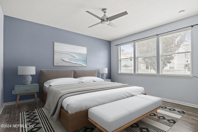 bedroom featuring ceiling fan, a textured ceiling, and dark hardwood / wood-style flooring