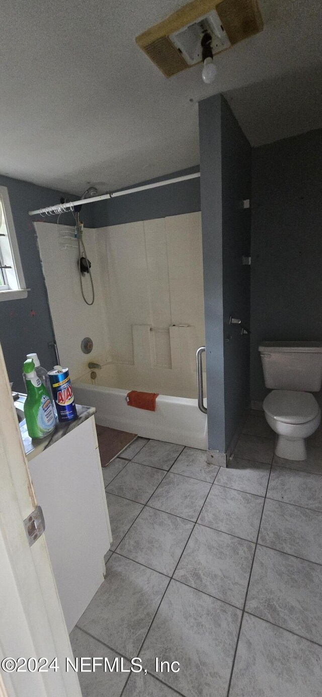 bathroom featuring shower / bath combination, tile patterned floors, a textured ceiling, and toilet