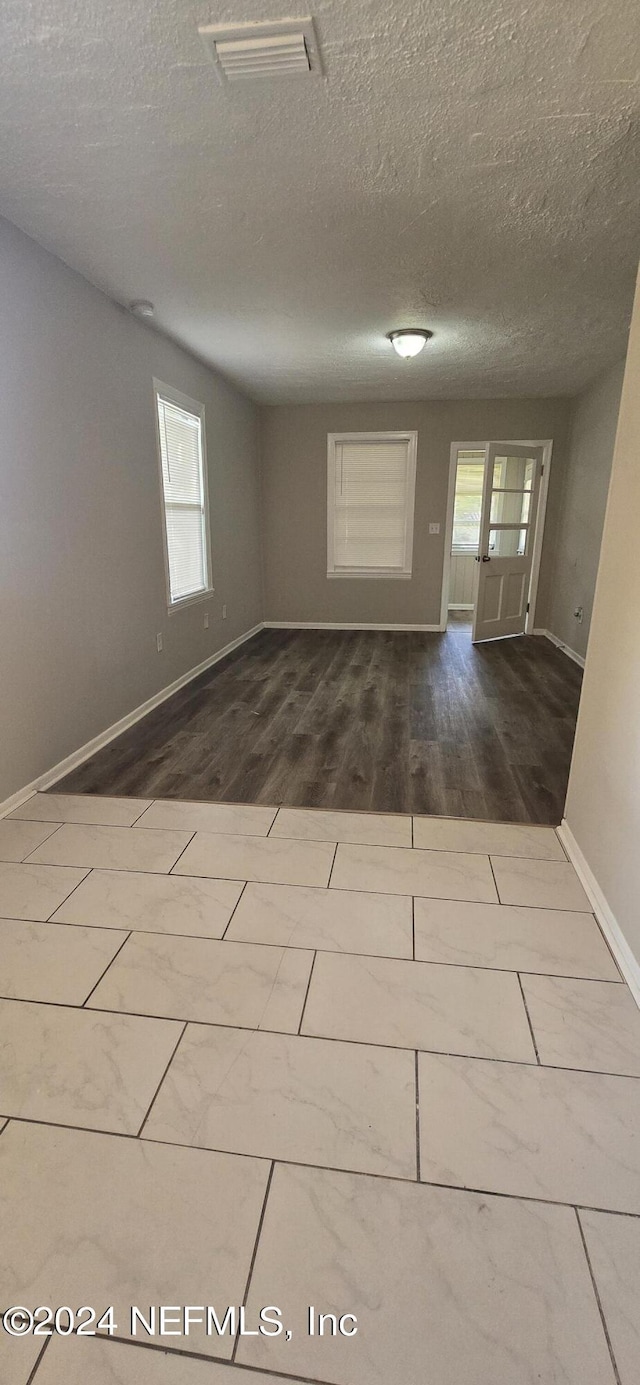 spare room featuring visible vents, dark wood finished floors, a textured ceiling, and baseboards