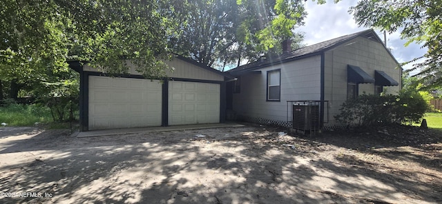 exterior space with an outbuilding, driveway, central AC, and an attached garage