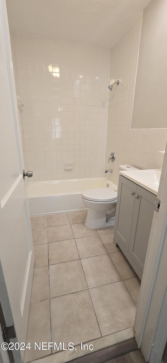 full bathroom with tile patterned flooring, toilet, shower / bath combination, vanity, and tile walls