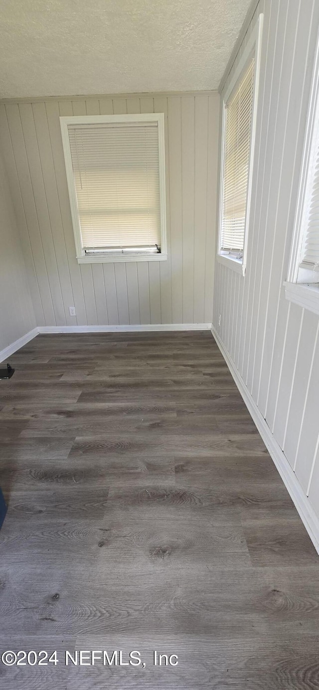 spare room with a textured ceiling, baseboards, and wood finished floors