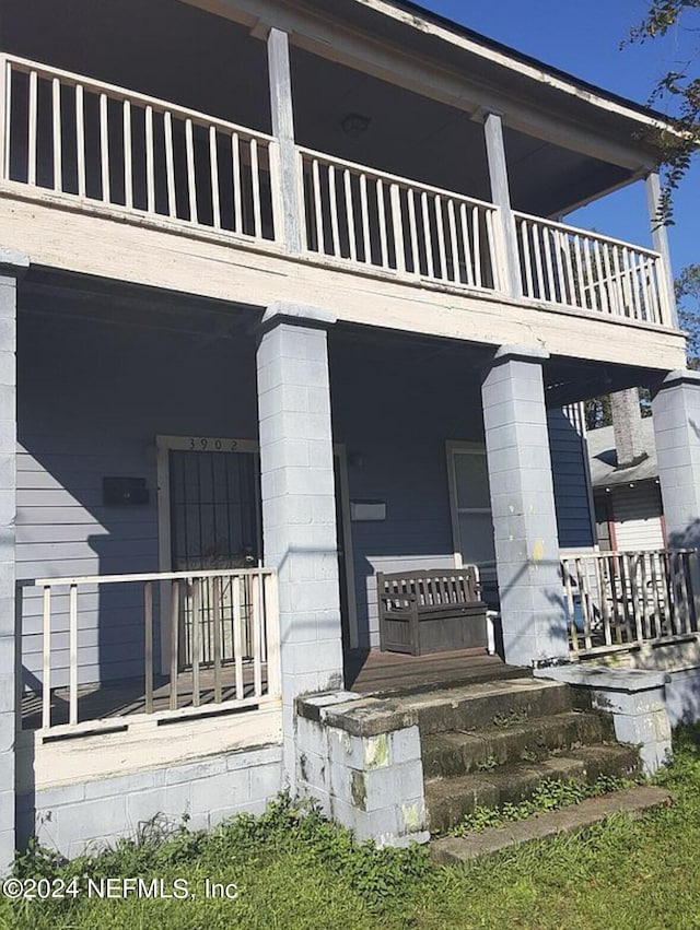 entrance to property featuring a balcony and covered porch