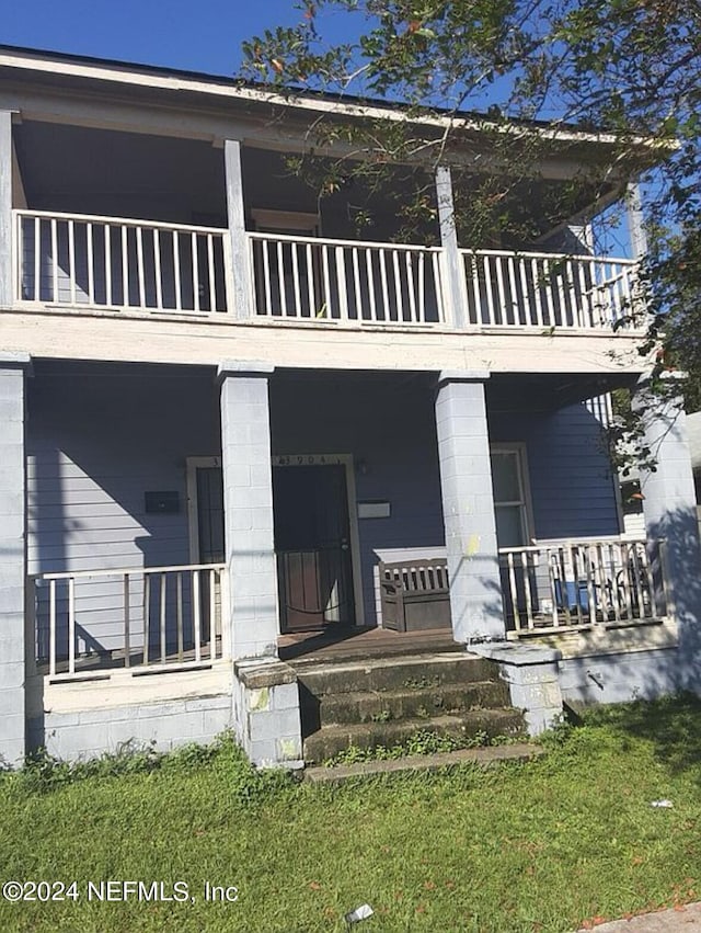 rear view of property featuring a porch and a balcony