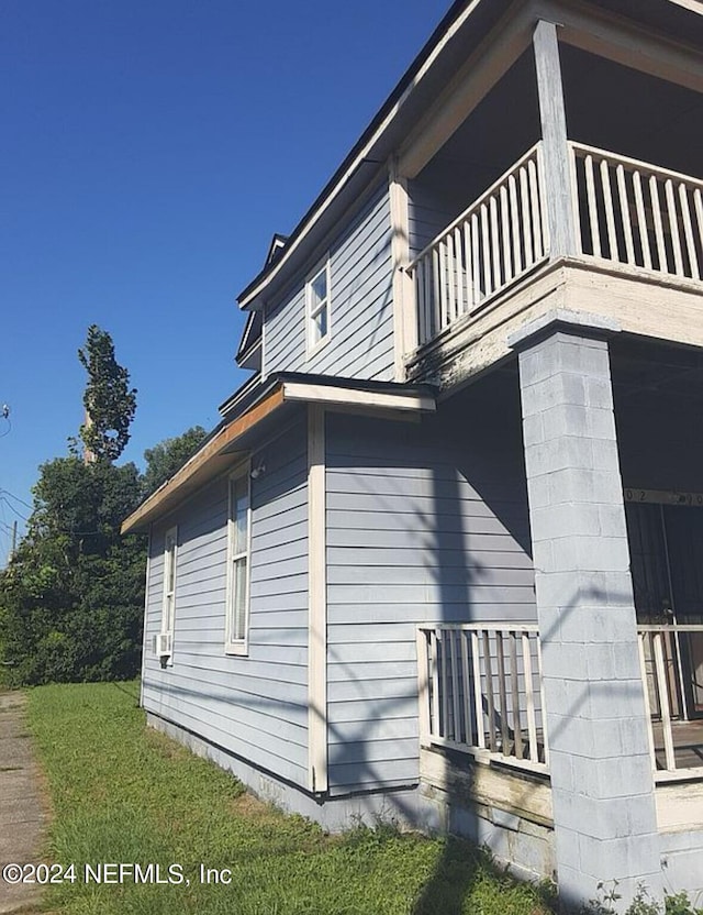 view of side of home with a balcony and a yard