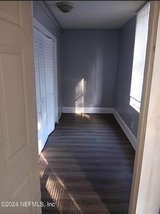 unfurnished bedroom featuring dark wood-type flooring, a closet, and a textured ceiling