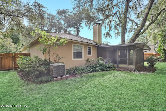 rear view of house with a lawn, a sunroom, and central air condition unit