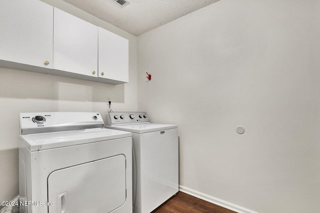 laundry room featuring cabinets, dark wood-type flooring, independent washer and dryer, and a textured ceiling