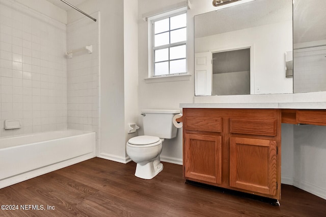 full bathroom with tiled shower / bath combo, vanity, hardwood / wood-style floors, and toilet