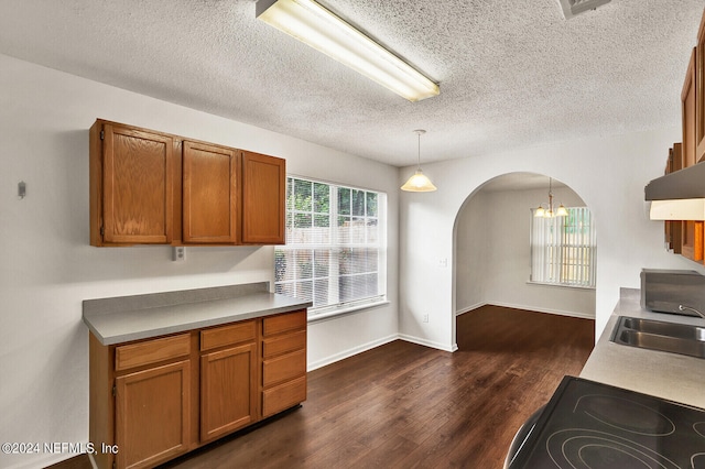 kitchen with a textured ceiling, sink, hanging light fixtures, an inviting chandelier, and dark hardwood / wood-style flooring