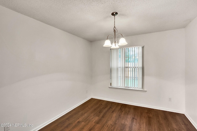 empty room featuring a textured ceiling, an inviting chandelier, and dark wood-type flooring