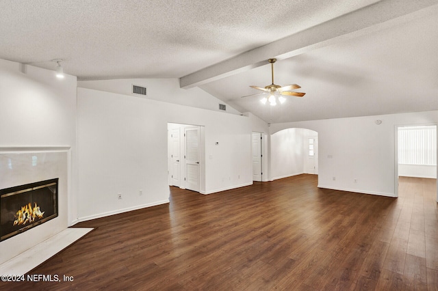 unfurnished living room featuring ceiling fan, a textured ceiling, lofted ceiling with beams, a fireplace, and dark hardwood / wood-style flooring