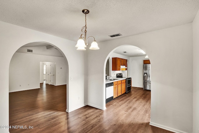 interior space featuring sink, a textured ceiling, appliances with stainless steel finishes, dark hardwood / wood-style floors, and an inviting chandelier