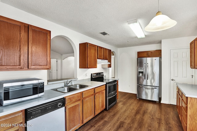 kitchen with a textured ceiling, dark hardwood / wood-style floors, sink, hanging light fixtures, and stainless steel appliances