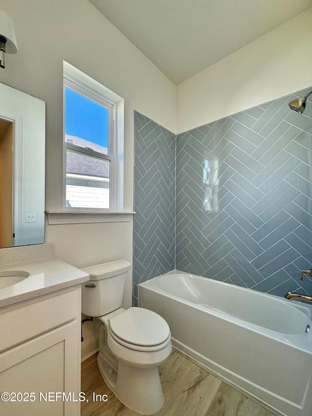 full bathroom featuring hardwood / wood-style flooring, tiled shower / bath, vanity, and toilet