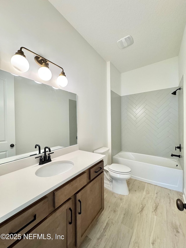 full bathroom featuring toilet, tiled shower / bath, a textured ceiling, vanity, and hardwood / wood-style floors