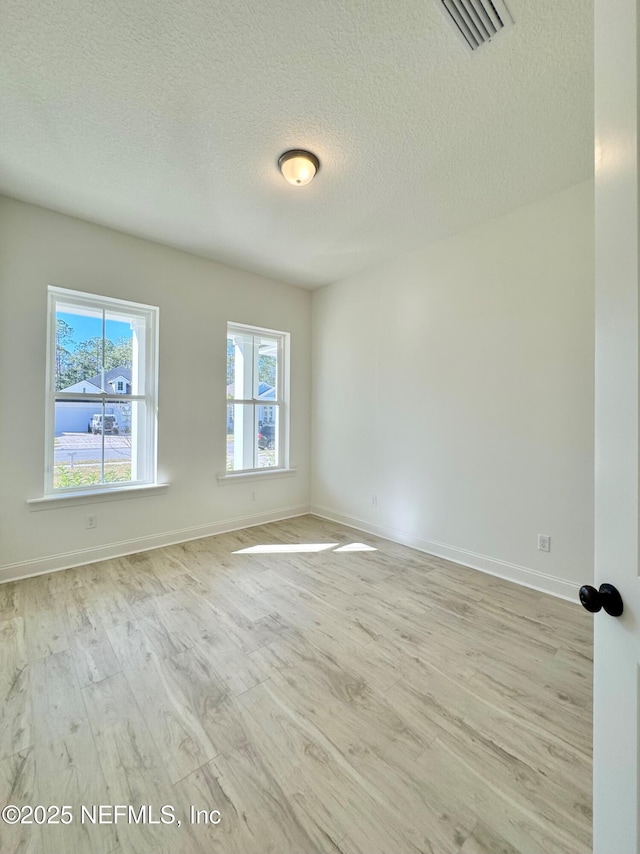 empty room with light hardwood / wood-style floors and a textured ceiling