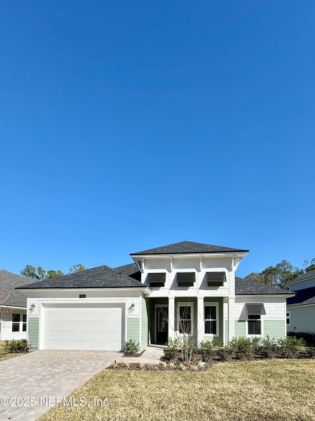 prairie-style house featuring a garage and a front lawn