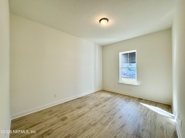 empty room with a textured ceiling and light hardwood / wood-style flooring